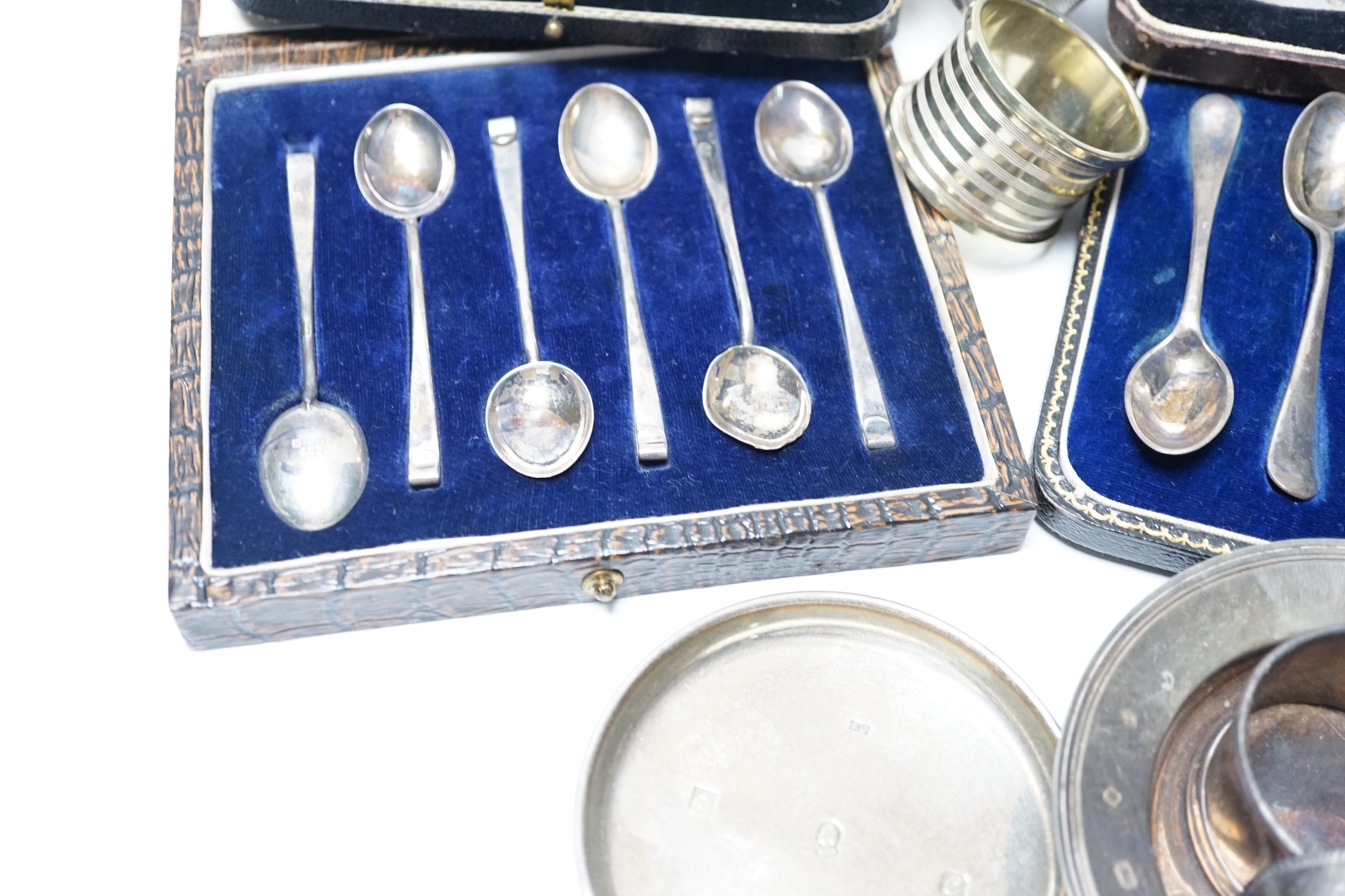 Four various silver serviette rings and a plated napkin ring, two small silver dishes, three various boxed sets of silver flatware and one part set of silver flatware.